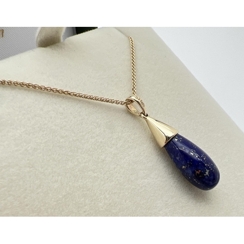 1064 - A modern design Lapis Lazuli and 9ct gold teardrop pendant. On an 18