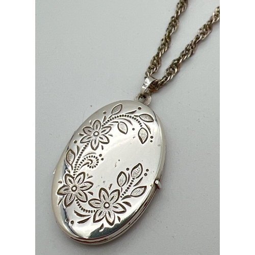 1066 - A vintage silver oval locket with floral engraving to front. On a 19