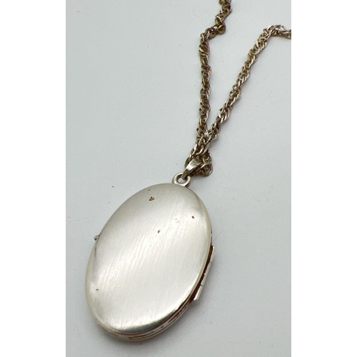 1066 - A vintage silver oval locket with floral engraving to front. On a 19