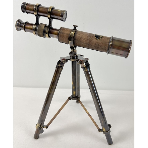 1315 - A brown leather bound brass desktop telescope on a folding tripod stand. Approx. 30cm tall.