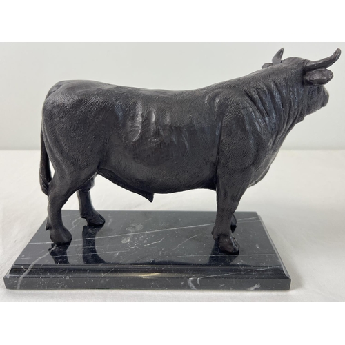 1142 - A bronze figure of a bull mounted on a black marble base. Approx. 17.5cm tall x 26cm long.