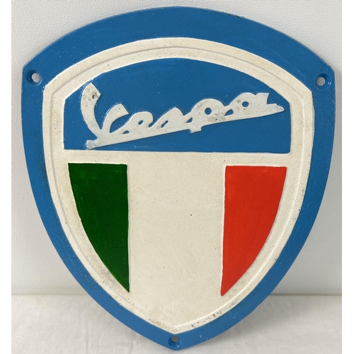 1292 - A Vespa shield shaped painted cast iron wall plaque. With fixing holes. Approx. 26cm x 21.5cm.