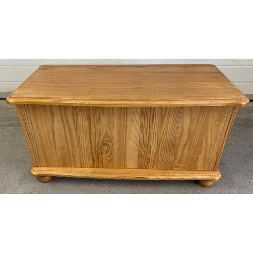 1438 - A modern pine blanket/toy chest with lift up lid and bun feet. Approx. 45cm tall x 86cm long.