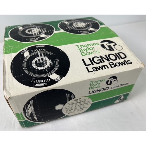 1338 - A set of 4 Thomas Taylor Lignoid lawn bowls. Size 2 mediumweight M-9450. In original box.