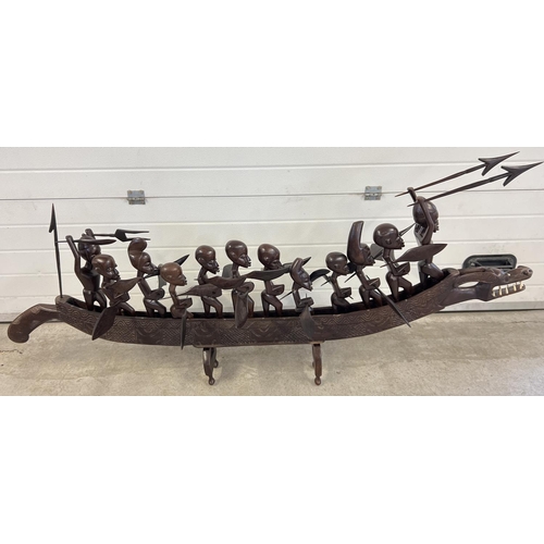 1276 - A large carved African sea dragon canoe with 12 carved African tribal figures each with a weapon. 10... 