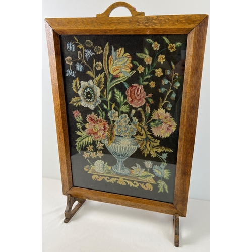 1342 - A vintage Art Deco oak framed needlepoint fire screen depicting a floral spray behind glass. Approx.... 