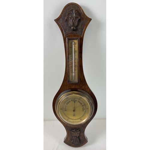 1202 - A vintage dark oak cased wall barometer with integral thermometer. Carved foliate design to oak case... 