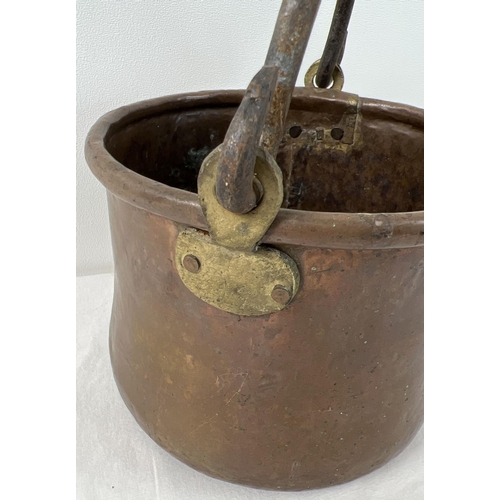 1153 - An antique copper and brass cooking pot with riveted iron swing handle. Approx. 14cm tall (excluding... 