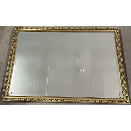 1450 - A floral design gilt framed wall hanging mirror. Approx. 67cm x 96.5cm.