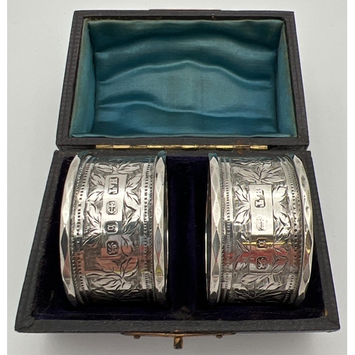 1122 - A pair of cased Victorian silver napkin rings engraved with decorative foliate design and each with ... 