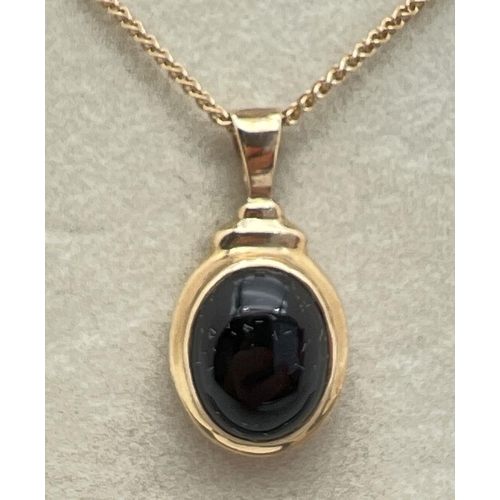 1127 - A boxed 9ct gold oval shaped pendant set with a cabochon of black onyx. On an 18