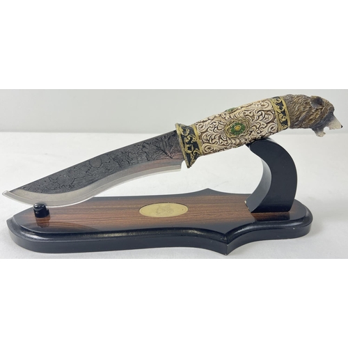 1229 - An ornamental survival style knife with display stand (a/f). Resin handle in the shape of a wolfs he... 