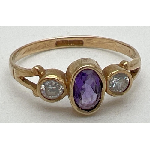 1002 - A 9ct gold, amethyst and cubic zirconia dress ring. Set with central bezel set oval amethyst flanked... 