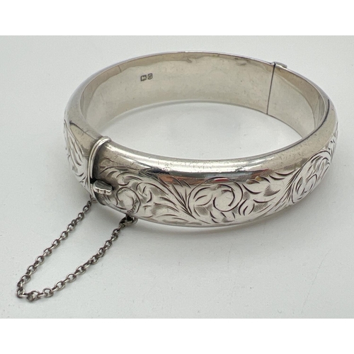 1005 - A vintage silver bangle with floral design engraving throughout, push clasp and safety chain. 1.5 cm... 