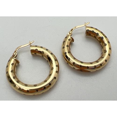 1027 - A pair of 9ct gold hoop earrings with polka dot decoration. Hallmarks to posts. Approx. 2.5cm across... 