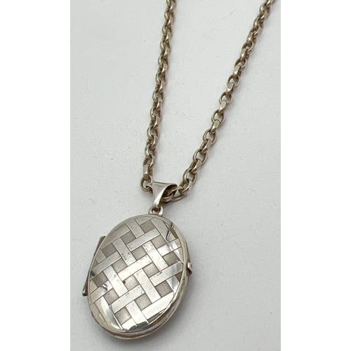 1032 - An oval shaped silver locket with engraved lattice design to front, on a 20