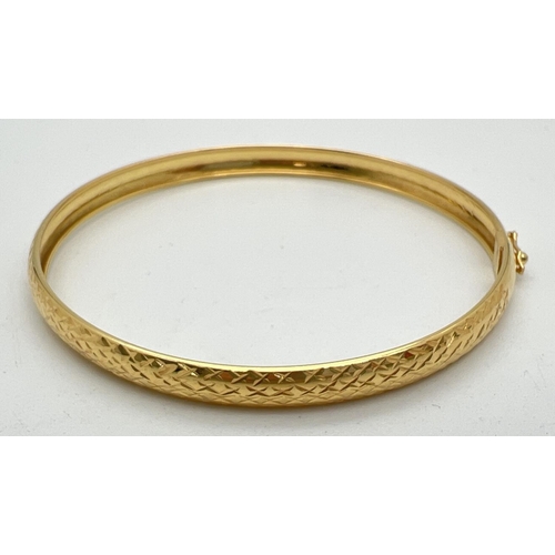 1041 - A modern silver gilt bangle with engraved diamond pattern throughout. With push clasp and safety cli... 