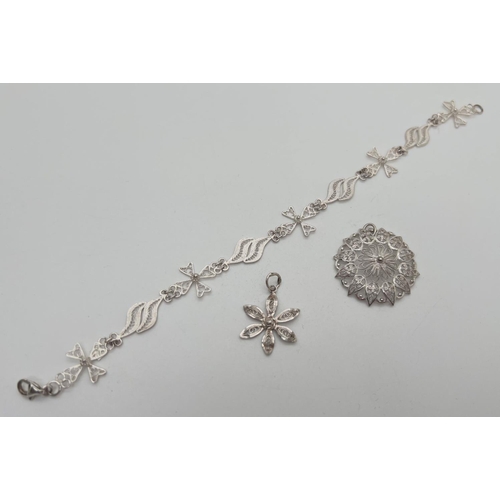 1044 - 3 pieces of silver and white metal filigree design jewellery. A small flower shaped pendant, a brace... 