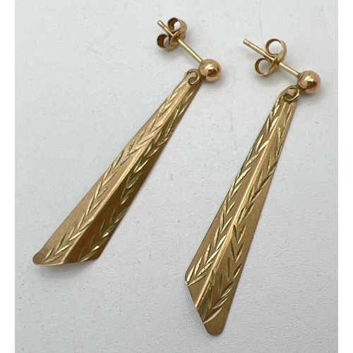 1069 - A pair of vintage style gold drop earrings with engraved leaf design to fronts. Test as 9ct gold. To... 