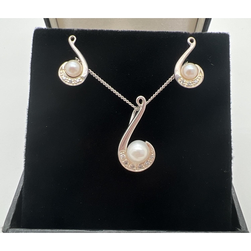 1090 - A modern design swirl design pendant necklace and matching earrings. Each set with a single pearl an... 