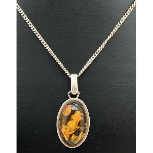 1091 - An oval shaped amber set silver pendant on an 18