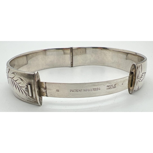 1092 - A vintage silver bangle with half engraved leaf decoration and slide push clasp. Hallmarked to insid... 