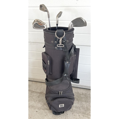 1398 - A Wilson black canvas golf bag and cover with contents, to include 6 Wilson 'Dualmetal' golf clubs. ... 