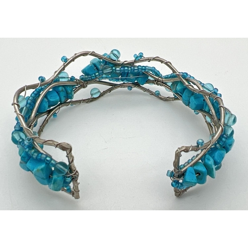 1107 - A white metal twisted design cuff bangle set with turquoise chips & small blue glass beads.