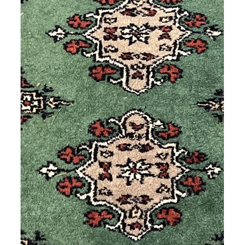 1495 - A small green ground Persian rug with beige, black and red design and tassled ends. Approx. 160cm x ... 