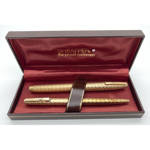 1181 - A boxed Sheaffer gold plated fountain pen and matching ball point pen with engraved engine turned de... 