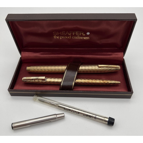 1181 - A boxed Sheaffer gold plated fountain pen and matching ball point pen with engraved engine turned de... 