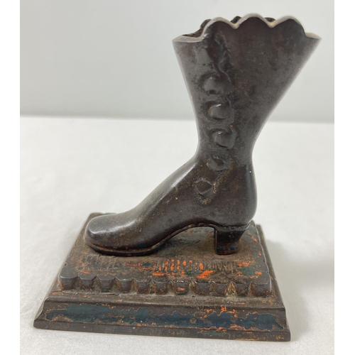 1196 - A vintage cast metal figure of a Victorian boot screwed onto a stepped base with remnants of origina... 