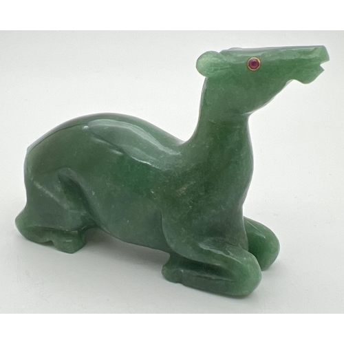 1427 - A carved jade figure of a deer, with ruby set eye (one missing). Approx. 6cm tall x 8cm long.