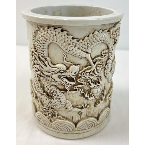 1318 - A Chinese white ceramic brush pot with dragon design shown in relief and shaped bottom rim. Impresse... 