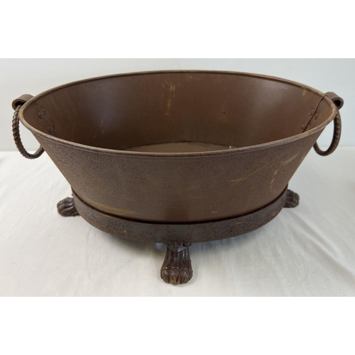 1198 - A small oval shaped metal fire pit with 4 claw feet, looped handles and rusted finish. Approx. 24cm ... 