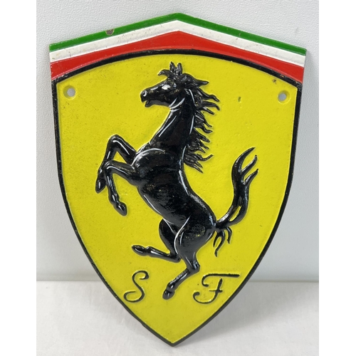 1381 - A painted cast iron wall plaque in the form of the Ferrari logo. With wall fixing holes, approx. 30c... 