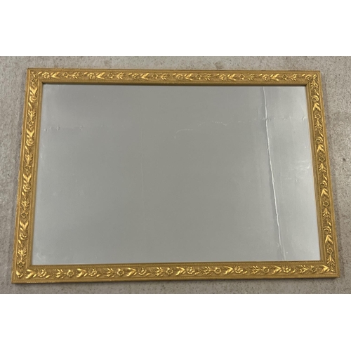 1509 - A gilt framed wall hanging mirror with floral design decoration to frame. Approx. 84 x 58.5cm.