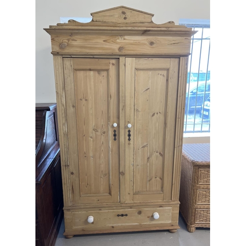 1517 - An antique pine 2 door wardrobe with central drawer and shaped top. Ceramic knob handles and decorat... 