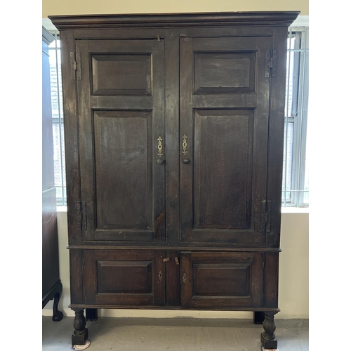 1518 - A Georgian dark wood 4 door cupboard with fixed interior shelves, raised on turned front legs. Origi... 