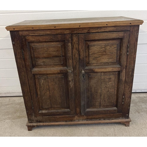 1529 - An antique dark wood 2 door cupboard with fixed interior shelving and panelled doors and sides. Appr... 