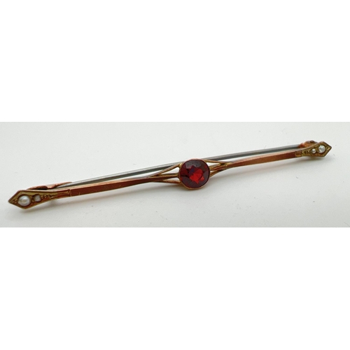 9 - An antique 9ct gold bar brooch set with a central round cut garnet and 2 small seed pearls to both e... 