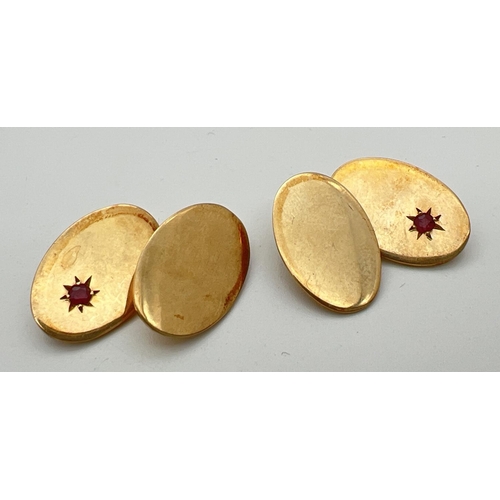 10 - A pair of vintage 9ct gold plain oval cufflinks set with a small ruby to each, by Britannic. Name an... 