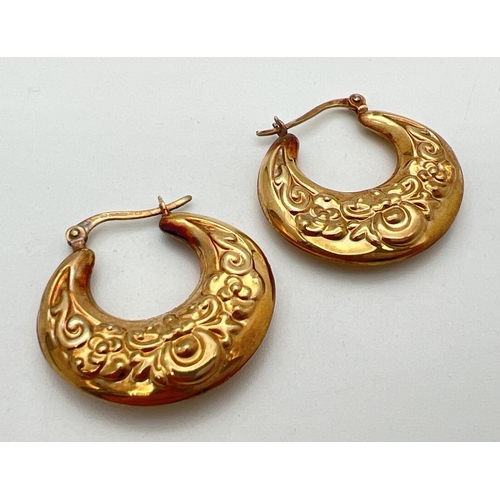 14 - A pair of 9ct gold creole style earrings with floral pattern and hinged posts. Approx. 2.75cm diamet... 