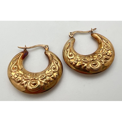 14 - A pair of 9ct gold creole style earrings with floral pattern and hinged posts. Approx. 2.75cm diamet... 