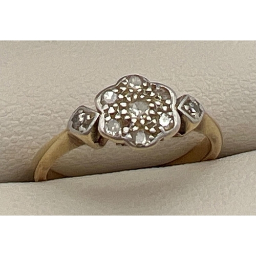 21 - An Art Deco 18ct gold and platinum diamond set ring. Floral style mount set with 7 small round cut d... 