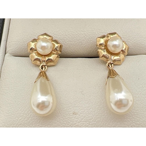 34 - A pair of 9ct gold and faux pearl drop style earrings. A teardrop shaped faux pearl with gold cap su... 