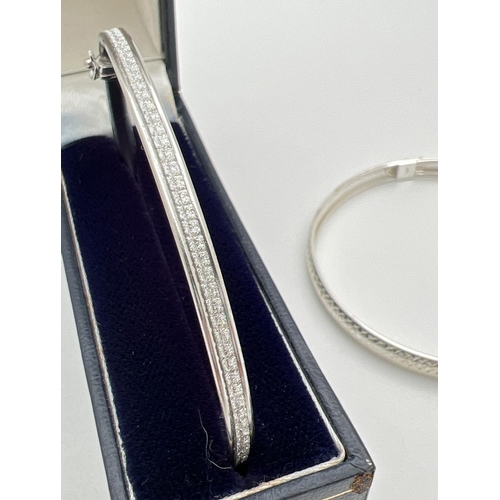 40 - 2 silver bangles, both with push clasps and safety clips. One with illusion stardust detail the othe... 