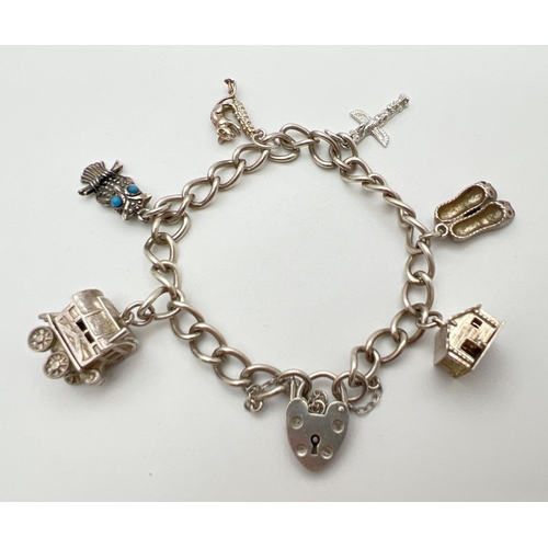 44 - A vintage silver charm bracelet with 6 charms, padlock and safety chain. Charms comprise: Wooden hou... 