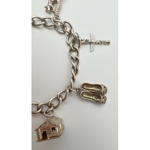 44 - A vintage silver charm bracelet with 6 charms, padlock and safety chain. Charms comprise: Wooden hou... 