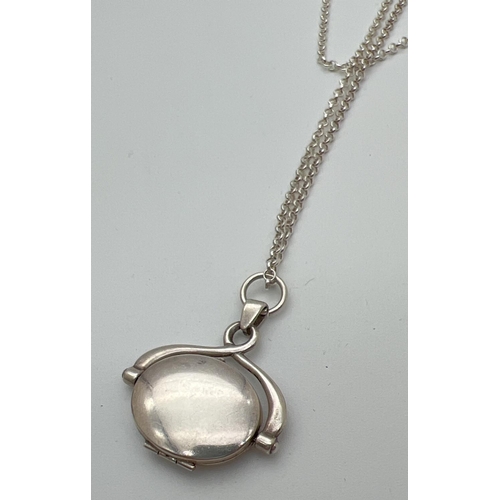 49 - A boxed silver oval shaped spinning locket on an 18